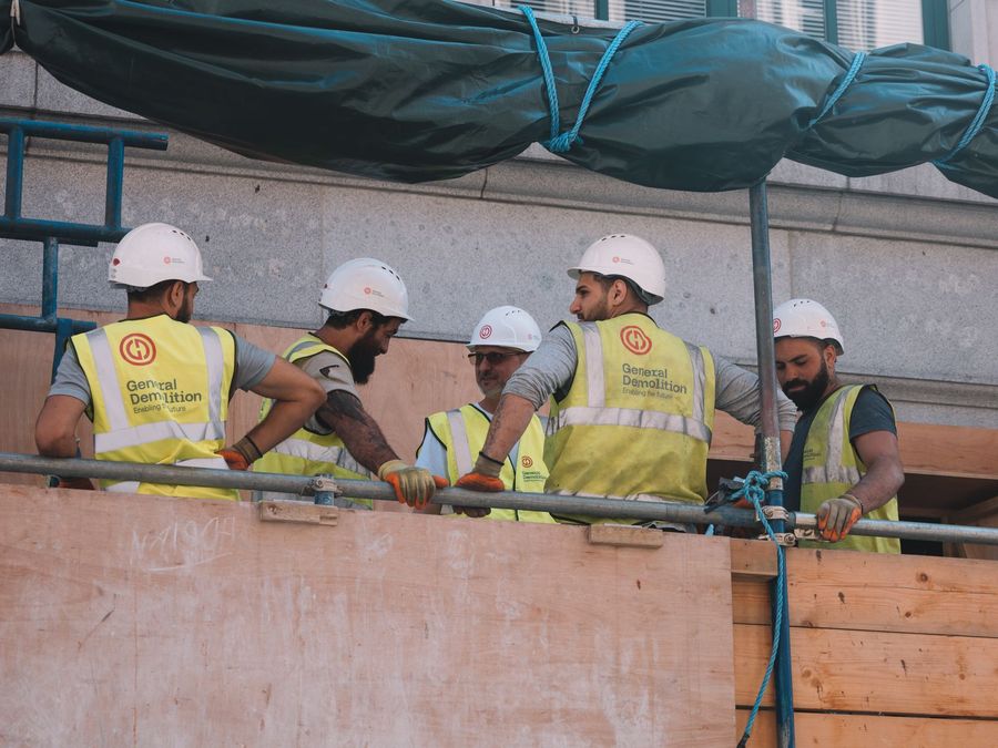 Cuadrilla de operarios con casco y chaleco trabajando sobre un andamio
