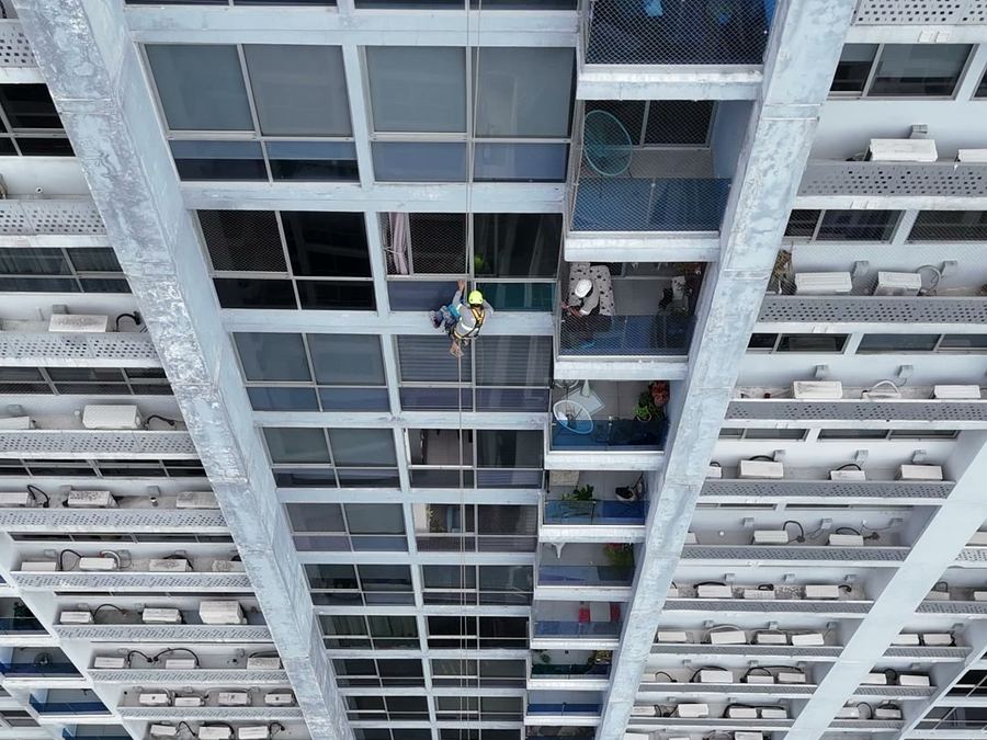 Vista cenital desde dron de un técnico descendiendo por cuerdas entre dos torres de un edificio residencial