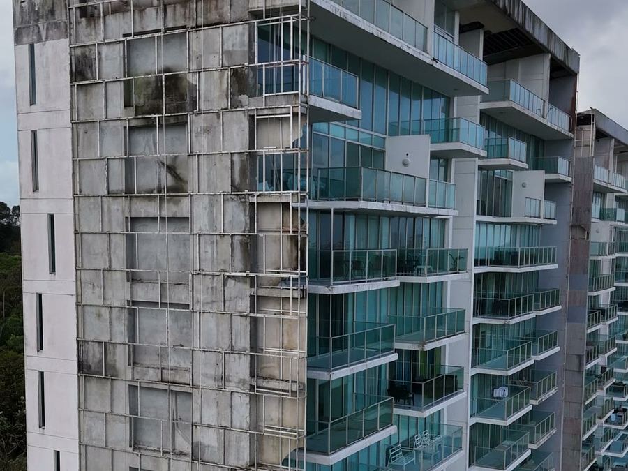 Guindola con cuadrilla trabajando sobre un paño de fachada de concreto en restauración, vista desde dron