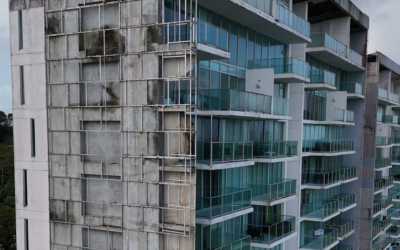 Guindola con cuadrilla trabajando sobre un paño de fachada de concreto en restauración, vista desde dron