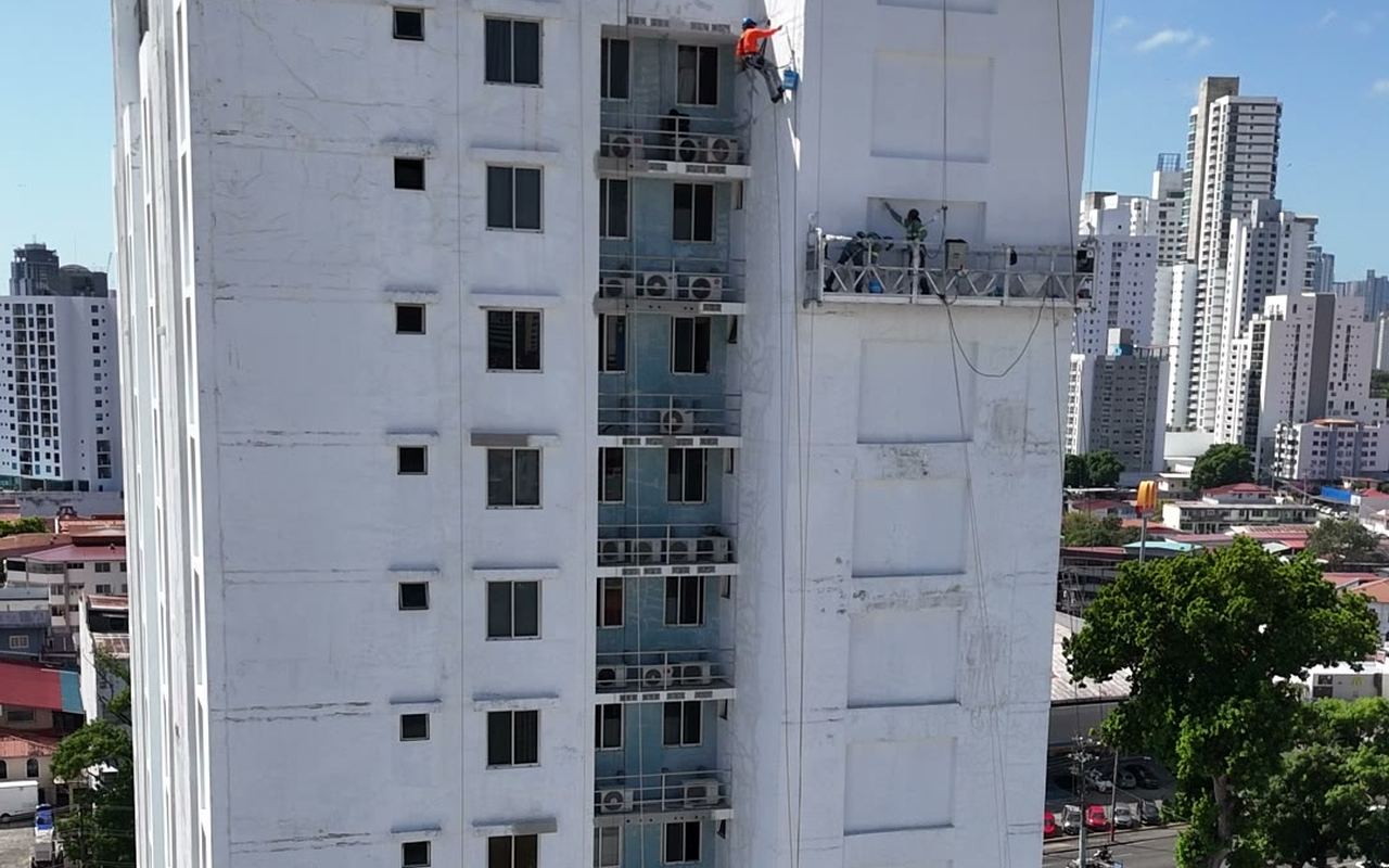 Torre residencial de gran altura en Ciudad de Panamá durante trabajos de fachada, con técnico en rope access y guindola montada